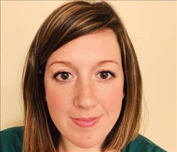 Female employee smiling against tan background