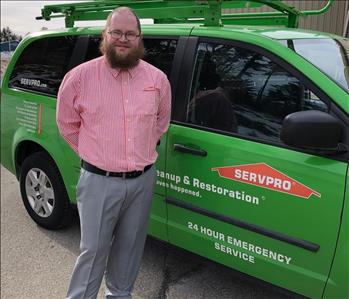 Male employee standing in front of SERVPRO van