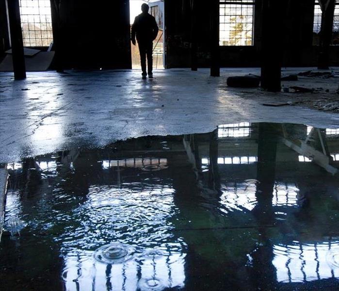 A warehouse with standing water and a person in a doorway. 