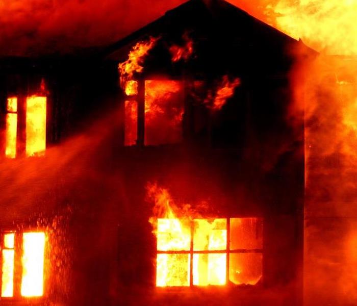 Fire blazing in a dark shadow of a home.