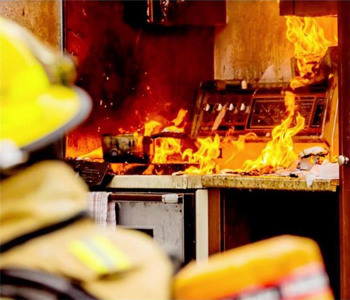 Firefighter looking at an active fire in a kitchen