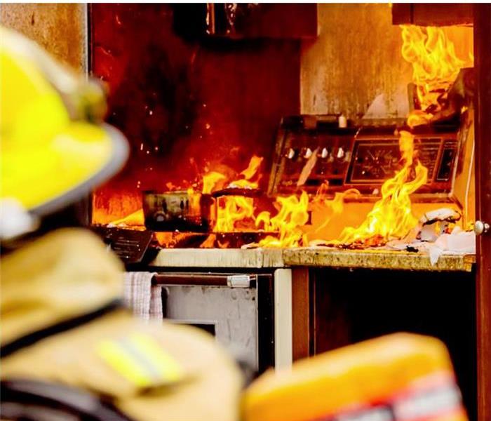 Firefighter looking at an active fire in a kitchen